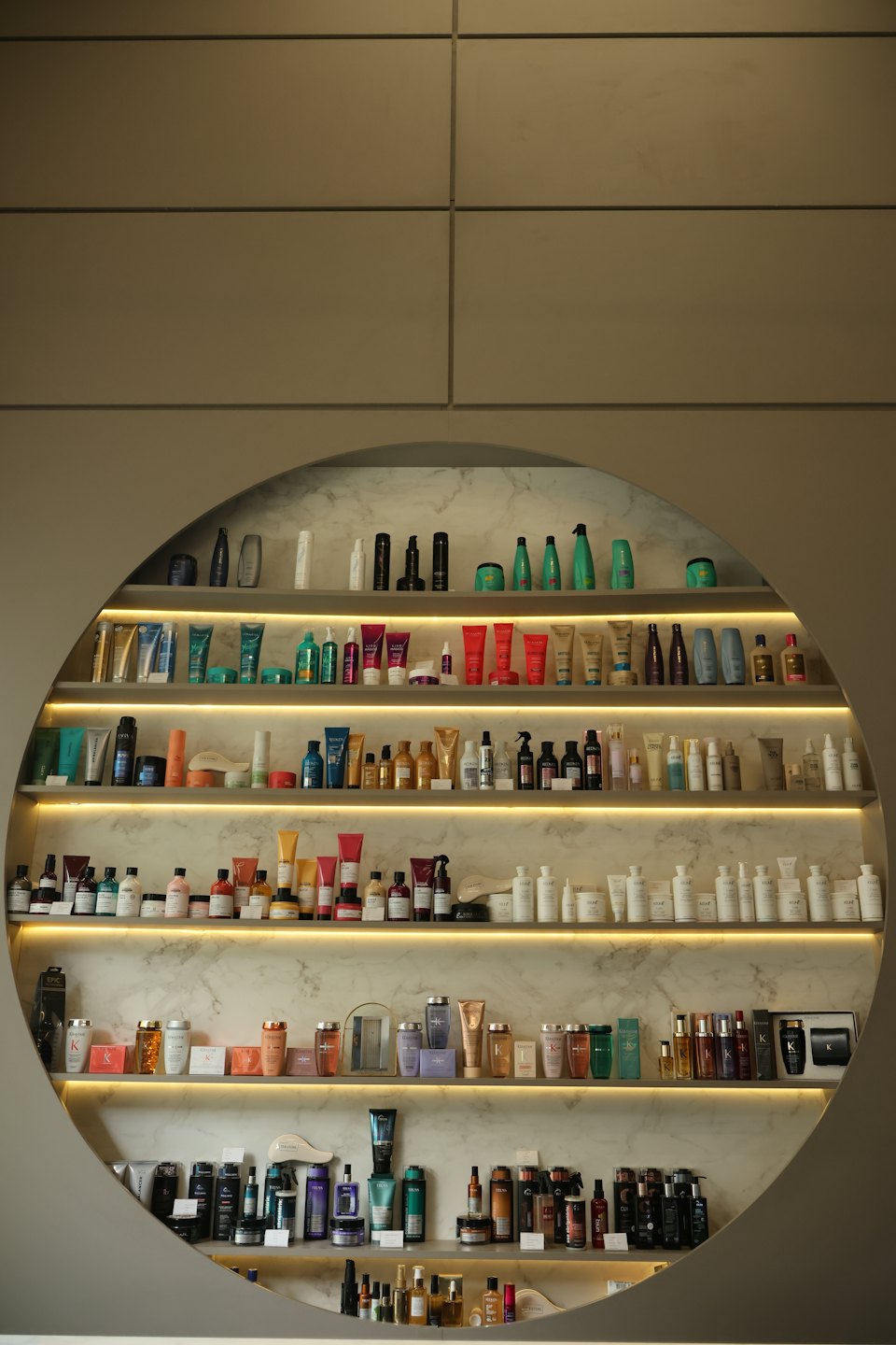 Rows of hair care products displayed on circular backlit shelves.