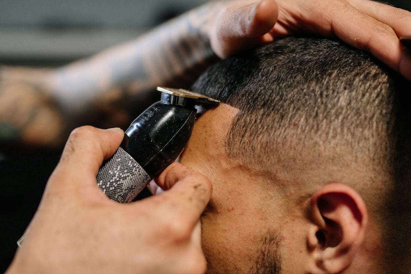 Barber uses an electric trimmer to shape a client's hairline.