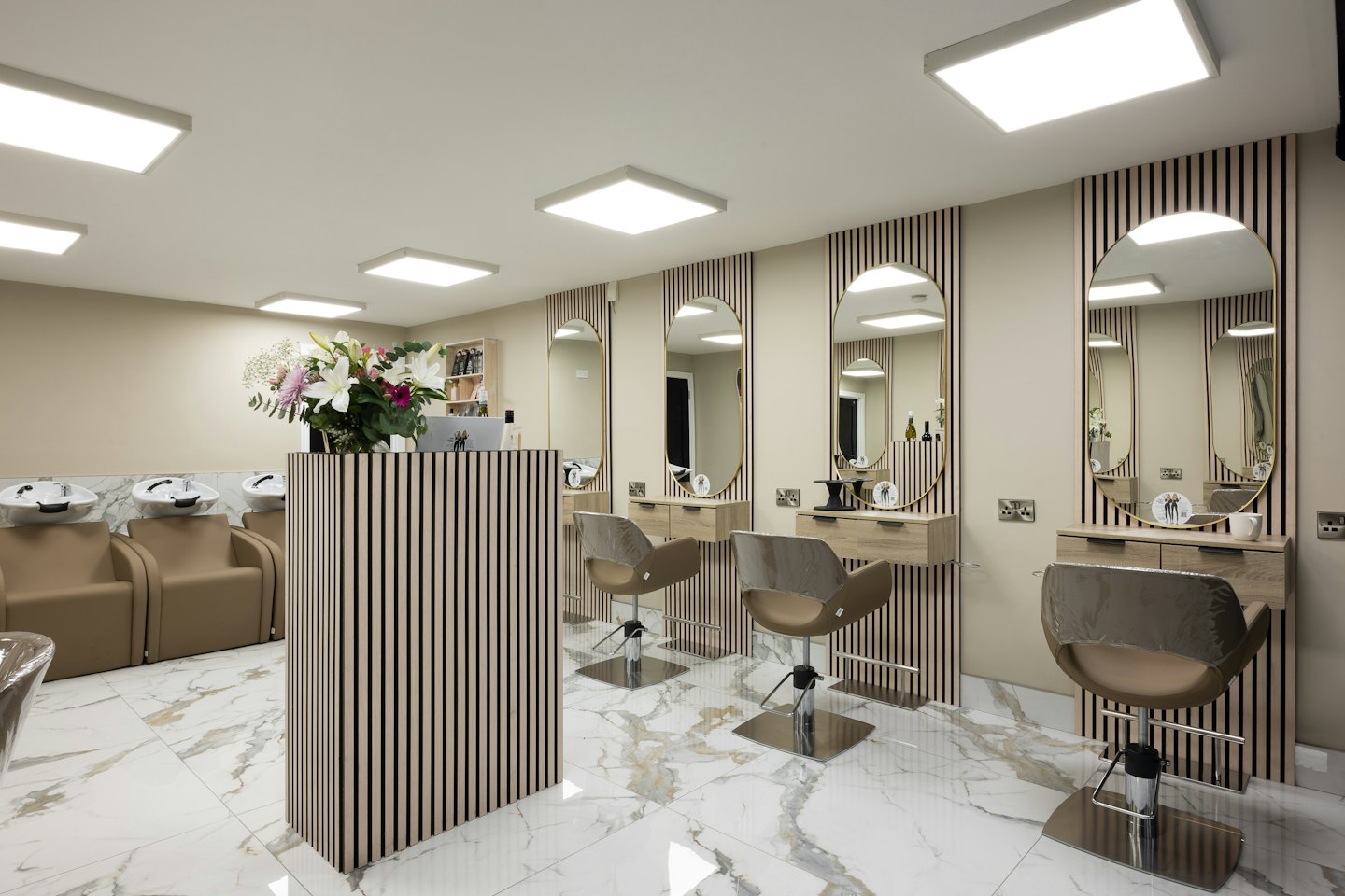 Modern hair salon interior with styling stations and wash area.