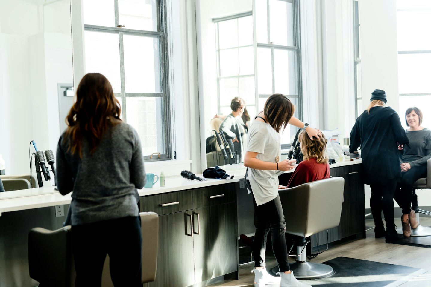 Stylist styling client's hair in a modern salon.